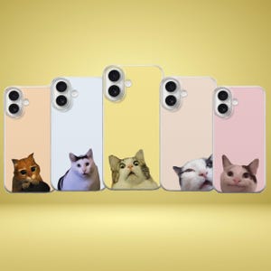 Puede incluir: Cinco fundas para teléfono en tonos pastel: melocotón, azul claro, amarillo, rosa pálido y rosa. Cada funda presenta un diseño diferente de cara de gato. Las fundas tienen recortes para la cámara y una cara de gato asomando por abajo.