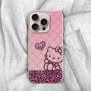 May include: Pink phone case with a plaid pattern, featuring a Hello Kitty design and a heart. The bottom section has a leopard print design. The case is designed for a smartphone.