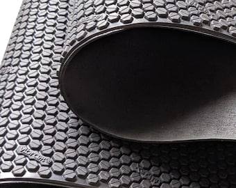 May include: Close-up of a black rubber exercise mat with a hexagonal pattern and the word "Vibram" printed on it.