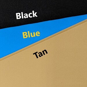 May include: Three fabric swatches, one black, one blue, and one tan. The swatches are arranged in a triangle shape, with the black swatch at the top, the blue swatch in the middle, and the tan swatch at the bottom.