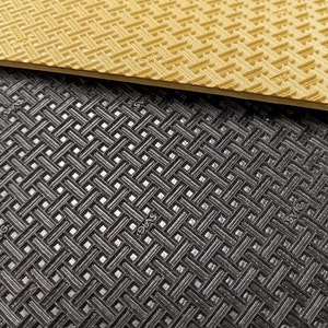 May include: Close-up of two textured surfaces. The top surface is a light brown with a grid pattern. The bottom surface is black with a similar grid pattern.