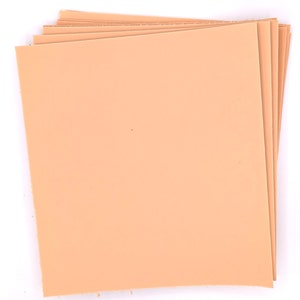 May include: A stack of peach-colored leather sheets. The sheets are smooth and have a slightly textured surface.