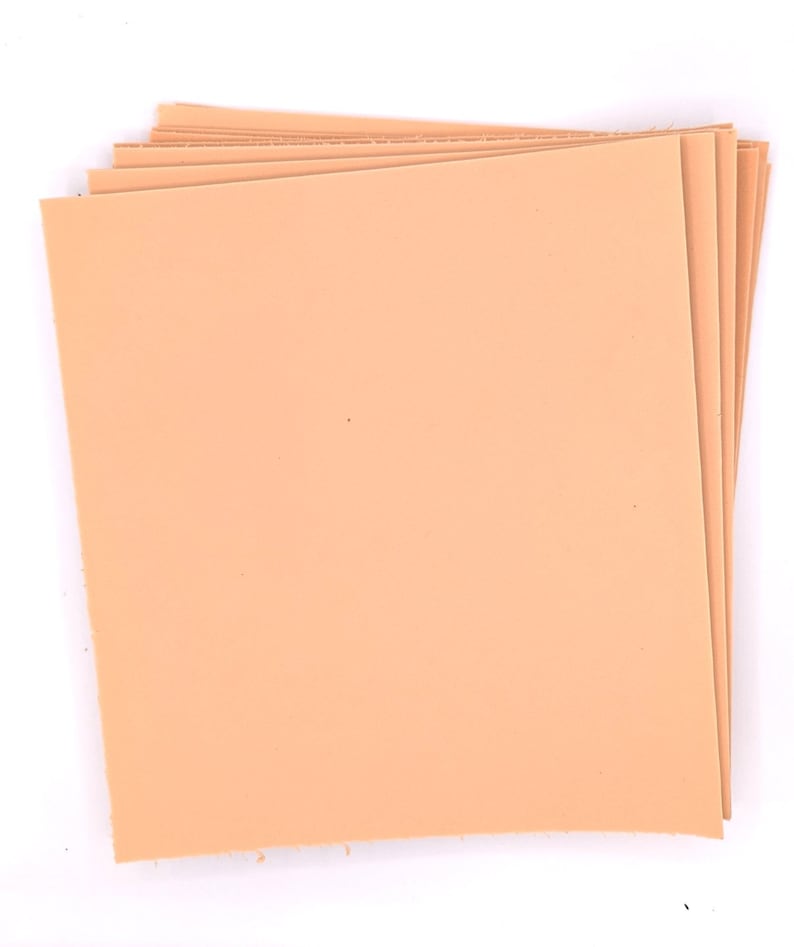 May include: A stack of peach-colored leather sheets. The sheets are smooth and have a slightly textured surface.