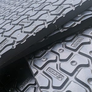 May include: Close-up of black rubber mats with a textured surface and the word "Vibram" embossed on the surface.