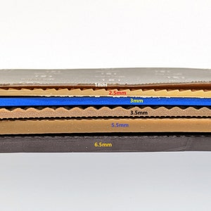 Pode incluir: Close-up de uma amostra de material em camadas com diferentes espessuras. As camadas s&atilde;o bege, marrom, azul e preto. As espessuras s&atilde;o etiquetadas em mil&iacute;metros: 1 mm, 2,5 mm, 3 mm, 3,5 mm, 5,5 mm e 6,5 mm.