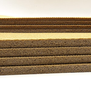 May include: A stack of brown foam sheets with a honeycomb pattern. The sheets are stacked on top of each other, creating a layered effect.