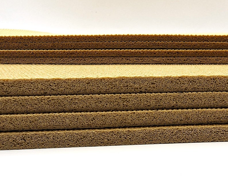 May include: A stack of brown foam sheets with a honeycomb pattern. The sheets are stacked on top of each other, creating a layered effect.