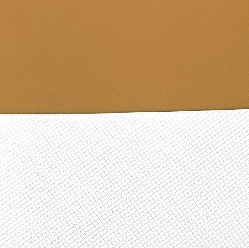 May include: A close-up of a textured surface with a brown top half and a white bottom half. The bottom half has a grid pattern.
