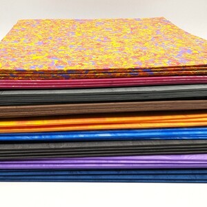 May include: A stack of colorful marbled paper sheets in various shades of red, yellow, blue, purple, orange, brown, and black.