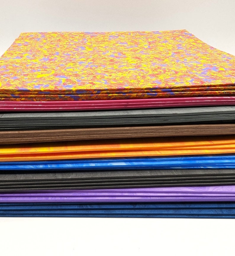 May include: A stack of colorful marbled paper sheets in various shades of red, yellow, blue, purple, orange, brown, and black.