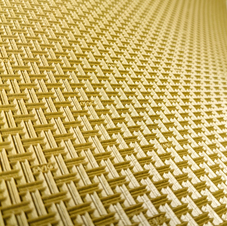 May include: A close-up of a gold-coloured textured surface with a repeating pattern of woven squares.
