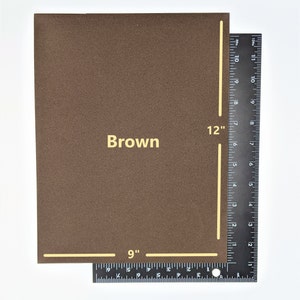 Pode incluir: Uma folha de papel kraft marrom medindo 30,5 cm por 22,9 cm. O papel tem uma superf&iacute;cie ligeiramente texturizada.
