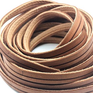 May include: A coil of brown leather strips, tightly wound. The strips are thin and appear to be made of genuine leather, with visible grain and texture. The color is a warm, medium brown, suggesting a natural dye or finish. The overall impression is of a craft supply.