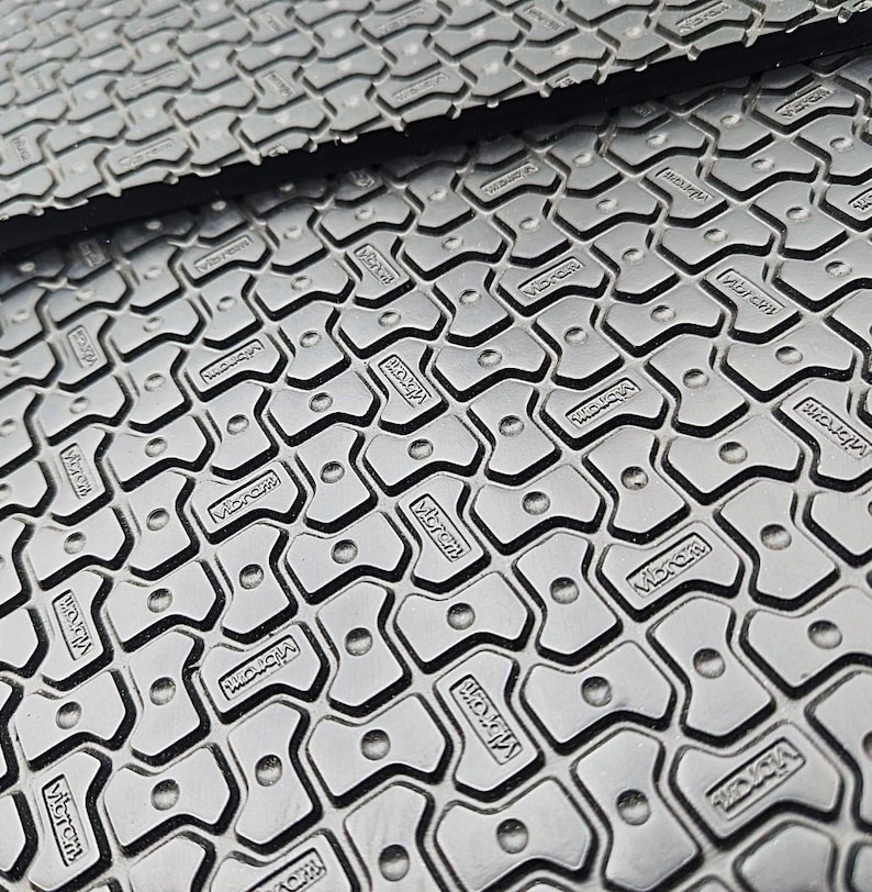 May include: Close-up of a black rubber mat with a repeating pattern of small, raised, star-shaped bumps. The mat has the word "Microfiber" embossed on each bump.