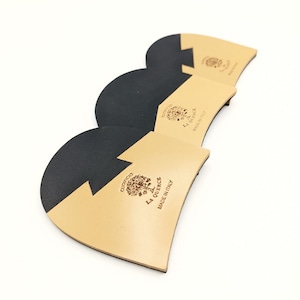 Op de afbeelding: Drie zwarte en beige leren hielbeschermers met de tekst "CUOIERCIO LA QUERCE MADE IN ITALY" erop gedrukt.