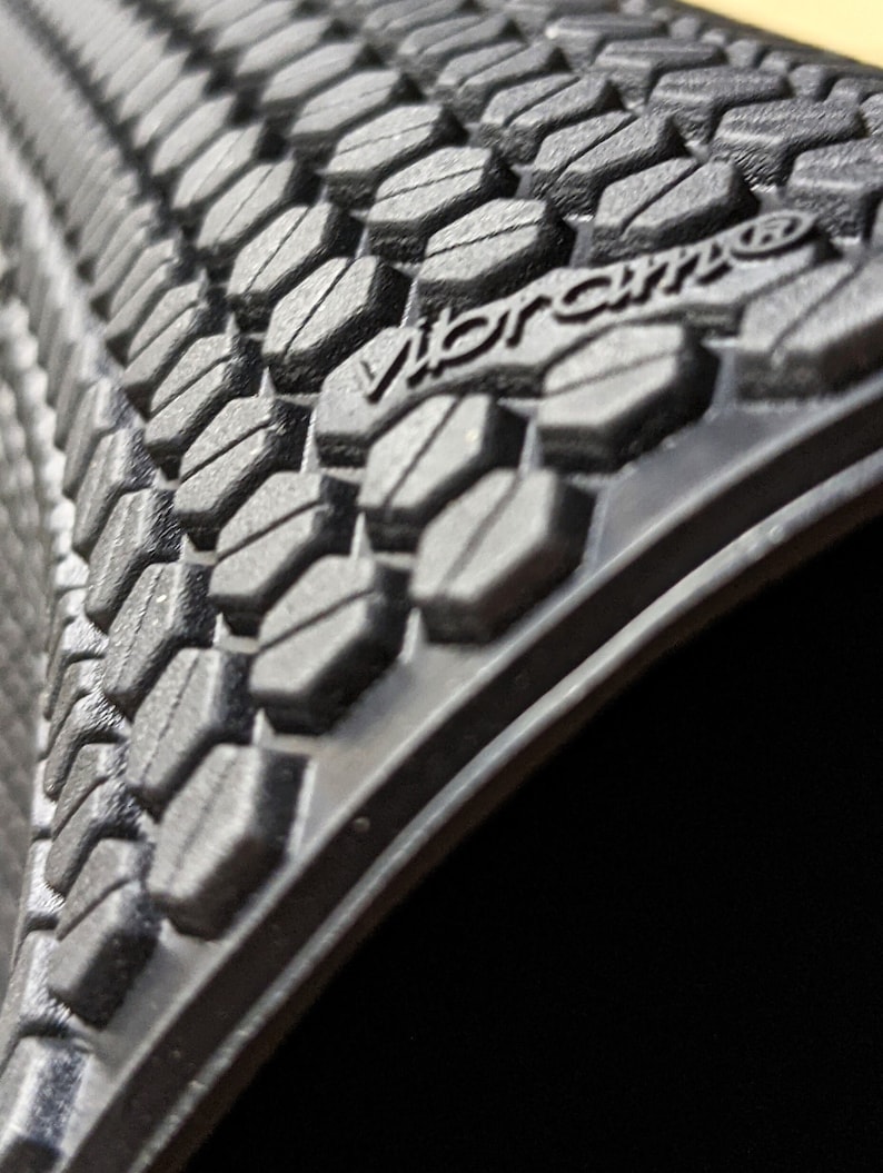 May include: Close-up of a black yoga mat with a textured surface and the word "Vibram" printed on it.