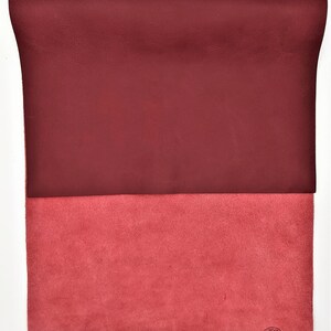 May include: A burgundy leather sheet with a suede underside. The suede side has a circular stamp that reads "INSPECTED".