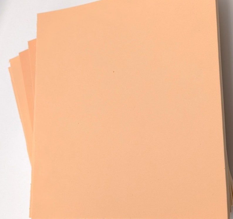 May include: A stack of peach-colored craft paper sheets.