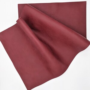 May include: A piece of burgundy leather with a textured surface. The leather is folded and appears soft and supple.