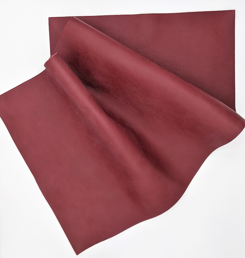 May include: A piece of burgundy leather with a textured surface. The leather is folded and appears soft and supple.