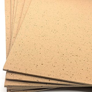 May include: A stack of light brown cork sheets with a textured surface and small dark spots. The sheets are rectangular and appear to be new. The cork sheets are stacked on top of each other.