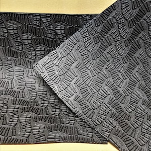 May include: Black textured rubber sheet with a repeating pattern of small, raised, oval shapes. The sheet is folded in half, revealing the same pattern on both sides.