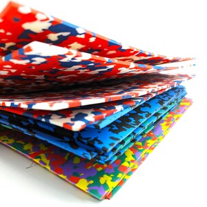 May include: A stack of colorful foam sheets with a camouflage pattern. The sheets are arranged in a staggered pattern, with the top sheet being red, white, and blue. The other sheets are blue, black, and purple.