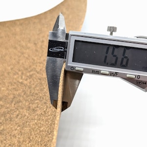 Puede incluir: Primer plano de un cuero marr&oacute;n con un calibre digital que mide el grosor del cuero. El calibre muestra 1,50 mm.