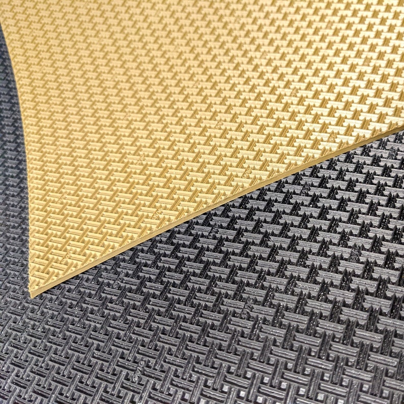 May include: Close-up of two textured surfaces. The top surface is a light gold colour with a diamond pattern. The bottom surface is black with a similar diamond pattern.