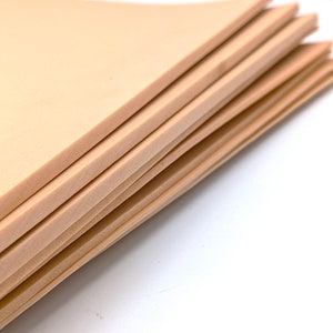 May include: A stack of beige foam sheets. The sheets are smooth and have a slightly textured surface.