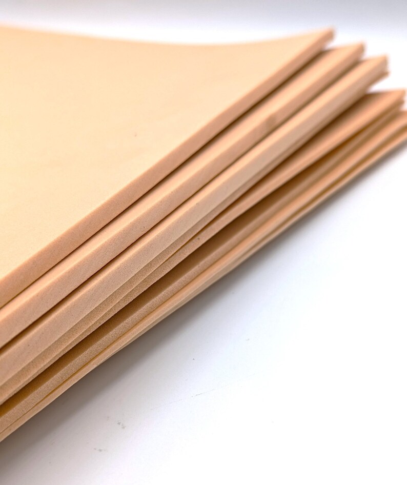 May include: A stack of beige foam sheets. The sheets are smooth and have a slightly textured surface.