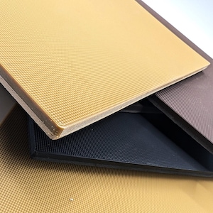 May include: Three pieces of textured rubber matting in different colors: beige, black, and brown. The beige mat is on top and the black mat is in the middle.