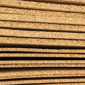 K&ouml;nnte beinhalten: Nahaufnahme eines Stapels rechteckiger Korkplatten. Die Platten sind hellbraun und haben eine strukturierte Oberfl&auml;che, die die nat&uuml;rliche Maserung des Korkmaterials zeigt. Die Platten sind ordentlich gestapelt, mit sichtbaren Kanten und kleinen L&uuml;cken zwischen den einzelnen Schichten.