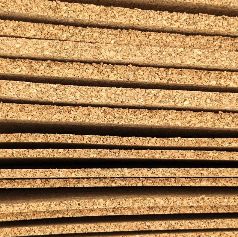 K&ouml;nnte beinhalten: Nahaufnahme eines Stapels rechteckiger Korkplatten. Die Platten sind hellbraun und haben eine strukturierte Oberfl&auml;che, die die nat&uuml;rliche Maserung des Korkmaterials zeigt. Die Platten sind ordentlich gestapelt, mit sichtbaren Kanten und kleinen L&uuml;cken zwischen den einzelnen Schichten.