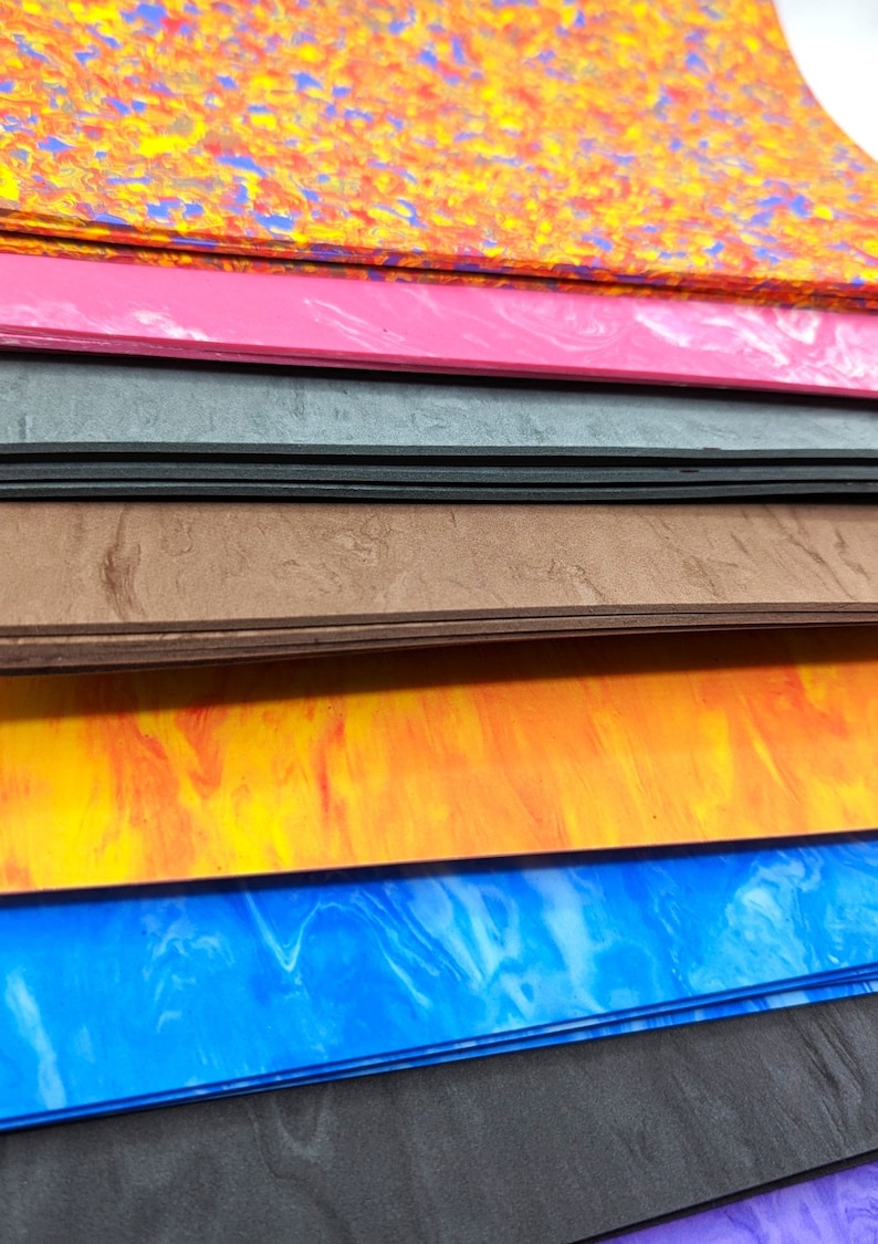 May include: A stack of colorful, marbled foam sheets in various shades of orange, pink, gray, brown, blue, and black.