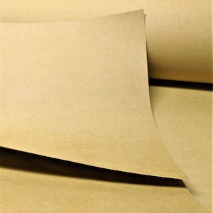 May include: A close-up of a sheet of brown craft paper. The paper is folded in half and the edges are visible. The paper has a slightly textured surface.