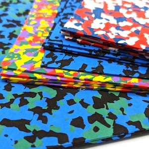 May include: A stack of colorful foam sheets with a camouflage pattern. The sheets are in various colors, including blue, green, red, yellow, and purple. The sheets are stacked on top of each other, and the top sheet is blue with black and green camouflage.