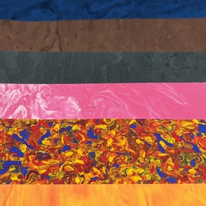 May include: A stack of colorful, marbled, and textured sheets of paper. The colors include blue, black, purple, brown, gray, pink, red, yellow, and orange.