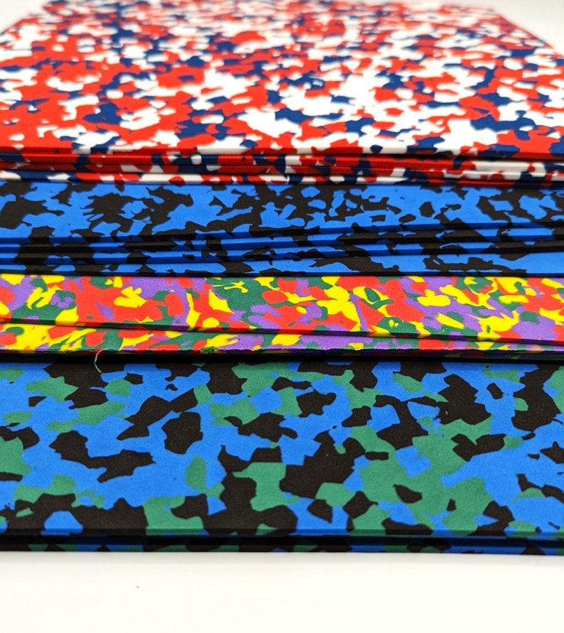 May include: Stack of colorful foam sheets with different abstract patterns. The top sheet is red, white, and blue. The second sheet is blue and black. The third sheet is purple, yellow, and red. The bottom sheet is blue, green, and black.