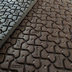 May include: Close-up of a brown rubber mat with a repeating pattern of interlocking shapes. The mat has the word "Vibram" embossed in the rubber.