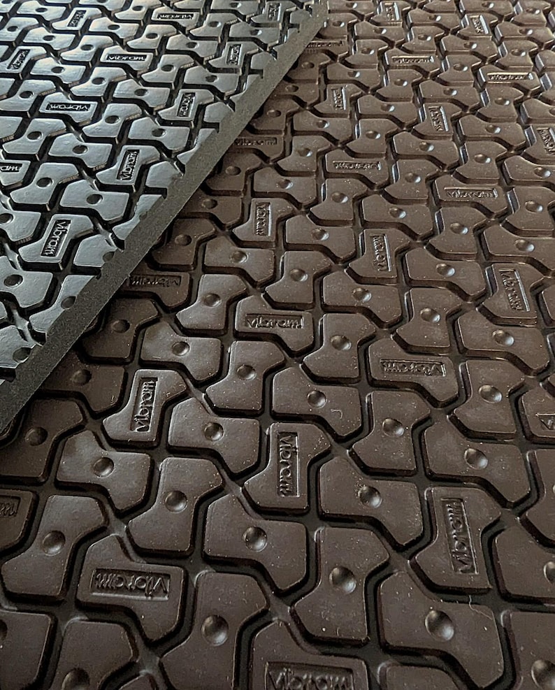 May include: Close-up of a brown rubber mat with a repeating pattern of interlocking shapes. The mat has the word "Vibram" embossed in the rubber.