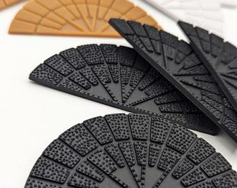 May include: Four half-circle shaped rubber floor mats in black, brown, and white. The mats have a textured surface with a pattern of small circles.