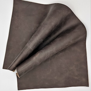 May include: A piece of brown leather folded in half. The leather has a distressed look and a rough texture.