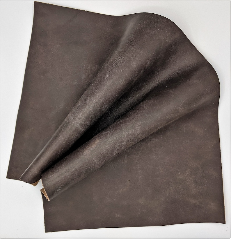 May include: A piece of brown leather folded in half. The leather has a distressed look and a rough texture.