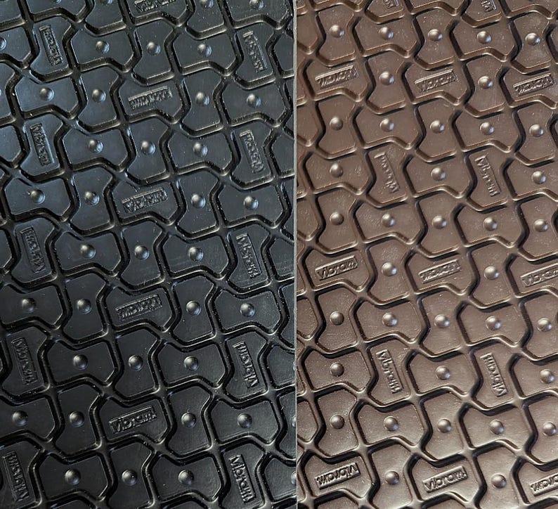 May include: Close-up of two black and brown textured rubber mats with the word "Vibram" embossed in a repeating pattern.