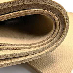 May include: Close-up of a beige foam mat rolled up, showing the layers of the material. The mat is textured and has a slightly rough surface.