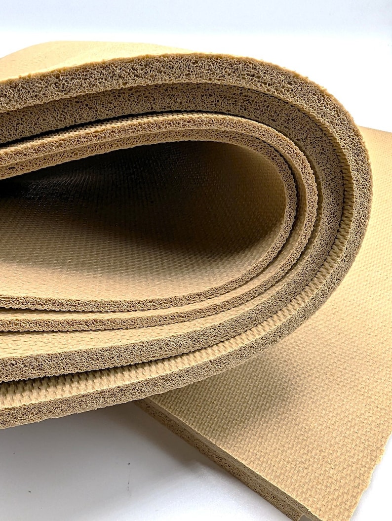 May include: Close-up of a beige foam mat rolled up, showing the layers of the material. The mat is textured and has a slightly rough surface.