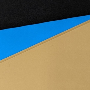 May include: A close-up of a tri-color background with a black top layer, a blue middle layer, and a tan bottom layer.