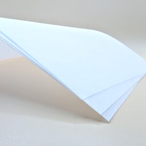 May include: Three sheets of white paper stacked on top of each other. The top sheet is folded over the other two sheets.