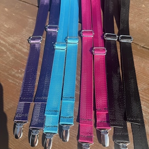 May include: A set of eight adjustable fabric straps in purple, bright blue, magenta, and black. Each strap features a silver-toned metal slider for length adjustment and a silver-toned metal clip at the bottom end for secure attachment.